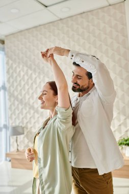 A bearded man and a redhead woman dance joyously in an office setting, bringing life and energy to the workspace. clipart