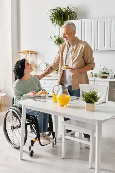 Man Wheelchair Lovingly Serves Food His Disabled Wife Kitchen Home — Stock Photo, Image