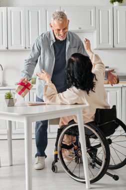 Bir adam, eşine evinin mutfağında tekerlekli sandalyede bir hediye verir..