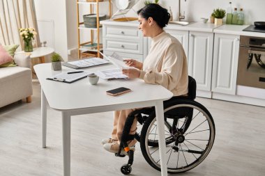 A disabled woman in a wheelchair engaging in remote work at a kitchen table. clipart