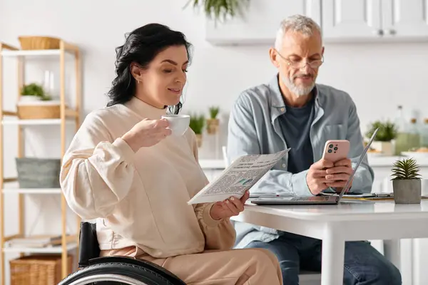 stock image A man and woman sit at a table, attentively reading newspaper, deep in thought in their cozy kitchen at home.