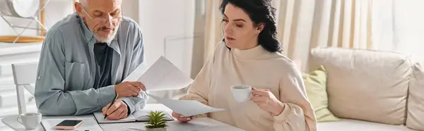 stock image A man and woman sit at a table, surrounded by papers, engaged in a serious discussion.