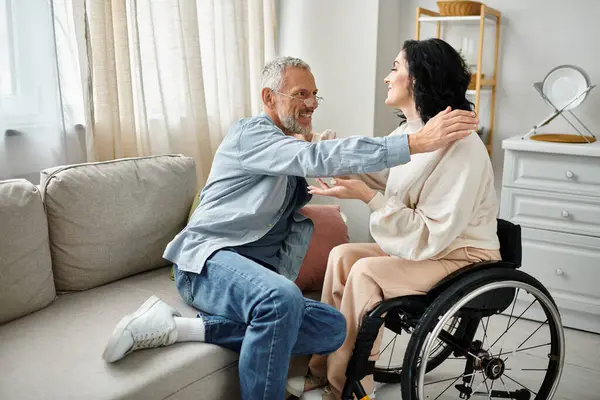 一位坐在轮椅上的残疾妇女正在客厅里以关心和支持的方式拥抱她的丈夫 — 图库照片