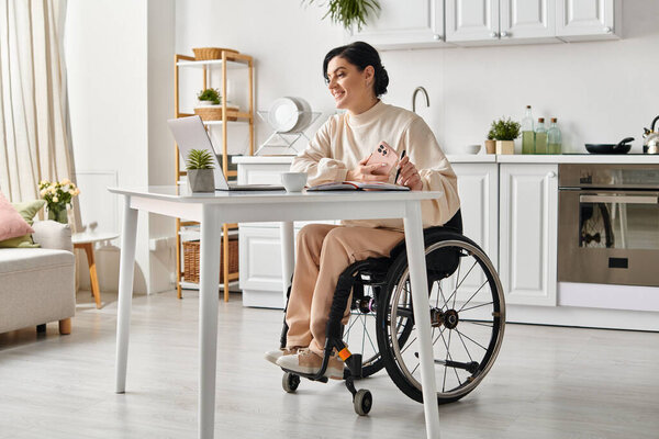 A woman in a wheelchair is focused and productive while working remotely at a table in her kitchen.