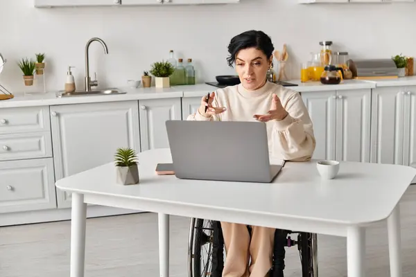Disabled Woman Wheelchair Sitting Kitchen Table Focused Her Laptop Computer — Stok fotoğraf