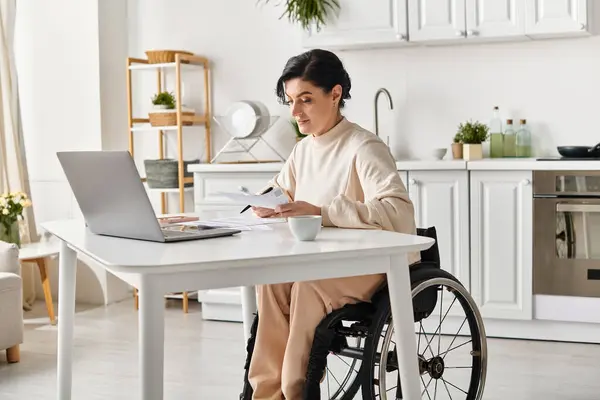 轮椅上的残疾妇女在厨房的笔记本电脑上远程工作 — 图库照片