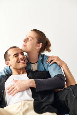 Two men sitting intertwined on top of each other in a loving embrace. clipart