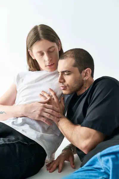 stock image Two men sit closely together on a bed, sharing a tender moment.