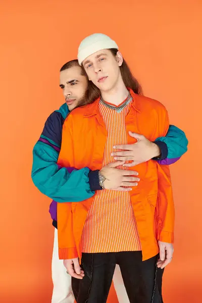 愛するゲイのカップルは大胆なオレンジ色の背景に対して側に立っています — ストック写真