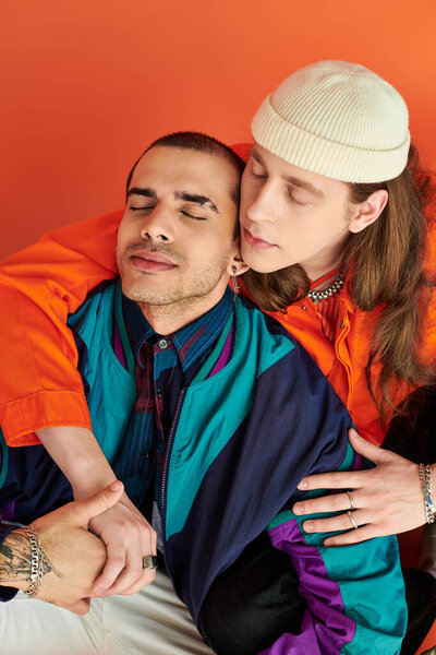 A loving gay couple, two men, sit closely together.