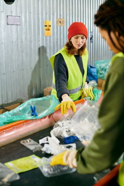 Two young volunteers in yellow and green vests sort trash together, embodying eco-conscious values through their actions.