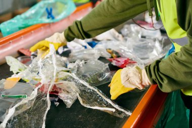 A young volunteer in a green shirt cleans a table, part of a group sorting trash in safety vests, promoting sustainability.