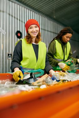 Two young volunteers in green vests and yellow gloves work together to sort trash in an eco-conscious effort.