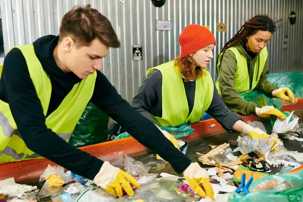 stock image A group of eco-conscious young volunteers in safety vests and gloves sorting through garbage together.