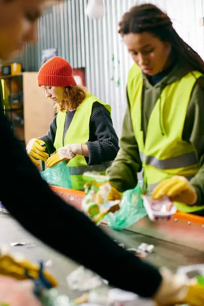 stock image Young volunteers in safety vests gather around a table filled with waste, showcasing their eco-conscious efforts.