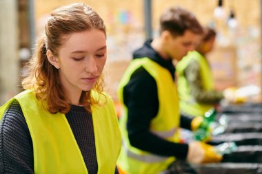 Young volunteers in yellow vests sorting trash together, showing eco-conscious efforts.