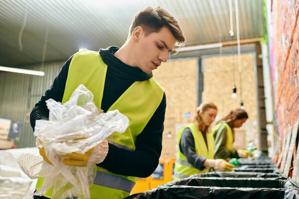 Young volunteer in yellow vest sorts trash into bin with eco-conscious team, making a positive environmental impact.