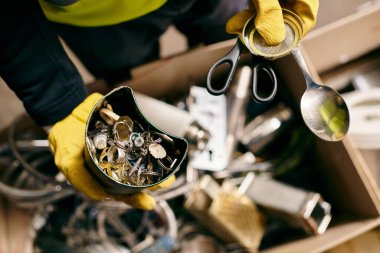 A passionate young volunteer, dressed in yellow gloves, holds a pair of scissors while sorting waste as part of an eco-conscious initiative.