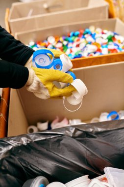 A young volunteer in gloves and safety vest holding plastic while sorting waste, staying eco conscious.