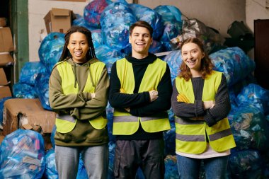 Three young volunteers in safety vests sorting plastic bags. Proactive in cleaning up the environment.