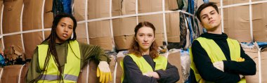 Group of young volunteers wearing safety vests and gloves standing next to recycling boxes, sorting waste.