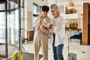 İki kadın, üst düzey bir lezbiyen çift, lobide kendilerini cep telefonuna kaptırmışlar..