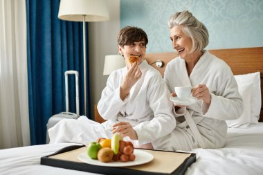 Couple of senior women sitting comfortably on a bed. clipart