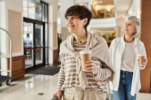 stock image Elderly lesbian couple strolling down hotel hallway.