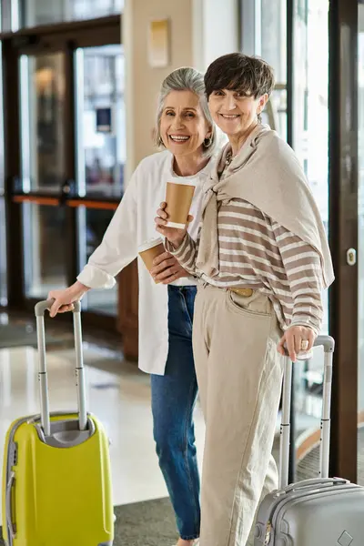 上了年纪的女同性恋夫妇站在旅馆里提着行李 — 图库照片