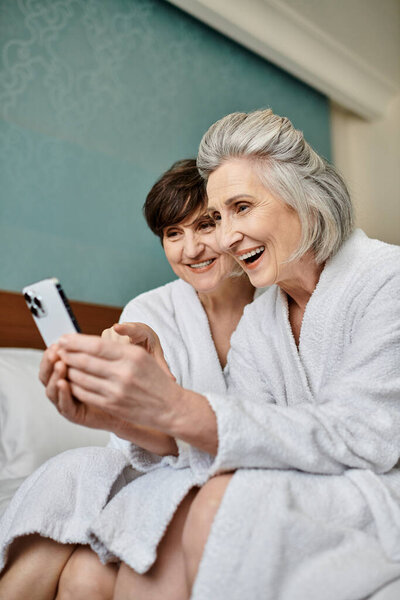 Старшая лесбийская пара разделяет нежный момент на уютной кровати.