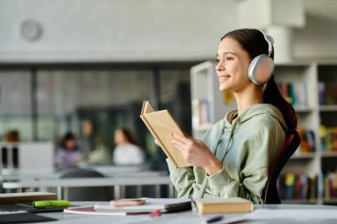 Kütüphanede kulaklık takmış bir kız kendi dünyasında edebiyat ve müzik karışımı bir şey buluyor..