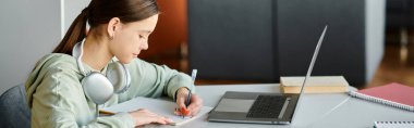 Genç öğrenci laptop açık, yenilikçi eğitim içeriği oluşturarak ev ödevi yapıyor.