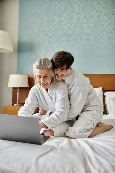 stock image Senior lesbian couple engrossed in laptop on bed.