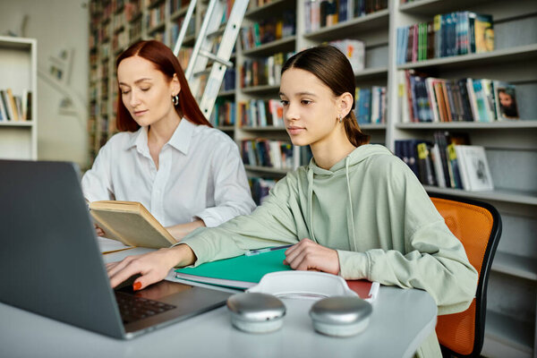 Рыжеволосый репетитор учит девочку-подростка в библиотеке, работая вместе над ноутбуком для современного образования.