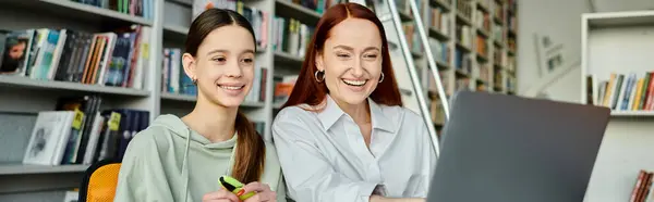 stock image tutor and a student, are engrossed in a laptop, engaged in after-school lessons in a library setting.