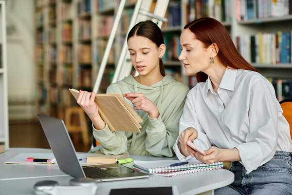 Рыжеволосый репетитор учит девочку-подростка в библиотеке, оба заняты ноутбуком для занятий после школы.