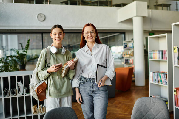 Рыжая женщина воспитывает девочку-подростка в библиотеке, внешкольные уроки современного образования.