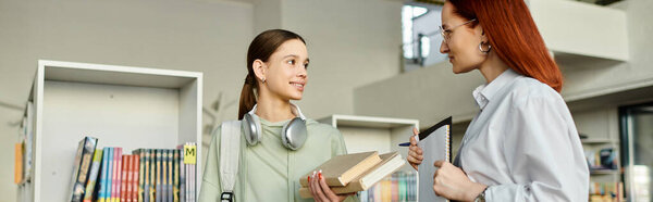 A redhead woman tutors a teenage girl in a library, banner