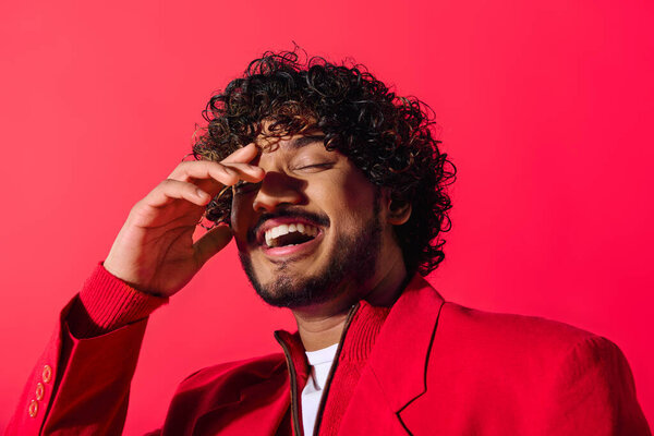 Молодой индиец в красной куртке разговаривает по телефону.