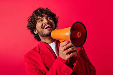 Handsome man holding red and orange megaphone. clipart