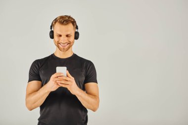 Kulaklıklı genç bir adam dijital dünyasına dalmış telefon ekranına bakıyor..