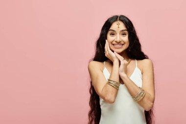 Çekici Hintli kadın, elleri zarif bir şekilde yüzüne yerleştirilmiş..