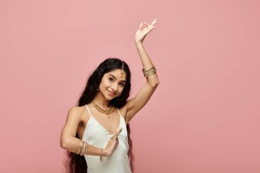 Graceful indian woman in white dress dancing on vibrant pink backdrop. clipart