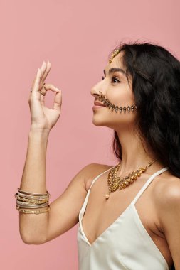 Young indian woman showcases gold jewelry with hand gesture. clipart