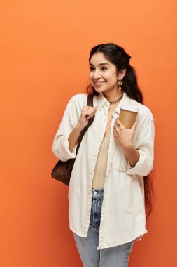 Beyaz gömlekli, kot pantolonlu, kahvenin tadını çıkaran genç Hintli kadın..