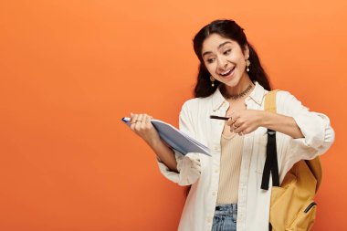 Genç Hintli kadın elinde bir defter tutarken enerjik bir şekilde işaret ediyor.
