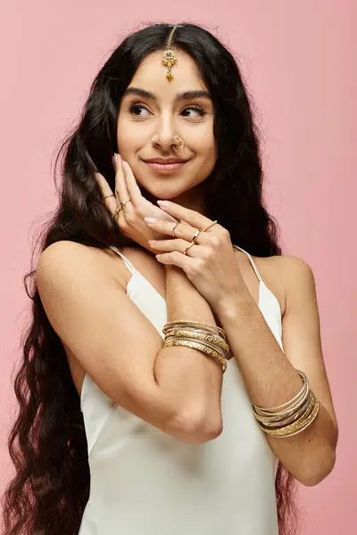 stock image indian woman with long hair striking a pose on a pink background.