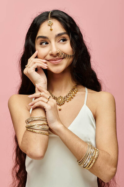 Изящная индийская женщина с длинными волосами и золотыми украшениями, ставящая позу.