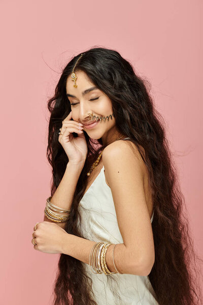 Захватывающая индийская женщина с длинными черными волосами, ставящая позу на ярком розовом фоне.