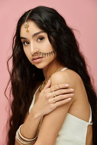 stock image A indian woman with long hair striking a pose on a vibrant pink background.